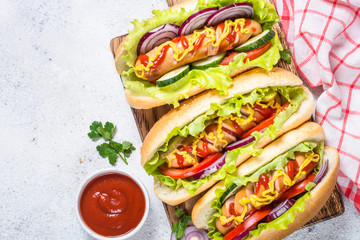 Hot dog with fresh vegetables on white top view.