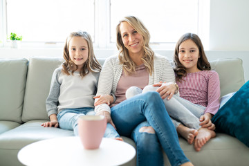 A Portrait of a beautiful mother and her little girls sitting at home and sharing a happy moment together.