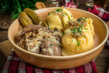 Fried chicken liver with onion served with mashed potatoes and pickled cucumber.