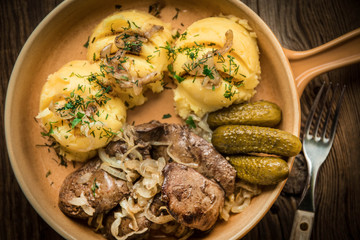 Fried chicken liver with onion served with mashed potatoes and pickled cucumber.