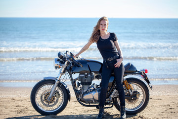 Obraz na płótnie Canvas Mujer de negro con motocicleta en la playa