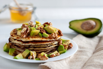 On the table there is a dish with pancakes, honey and nuts.