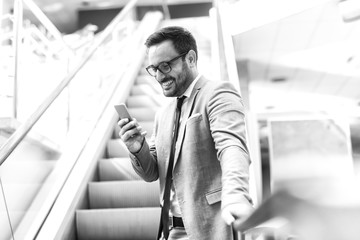 Close up of businessman using smart phone for writing or reading message while standing on the stairs.