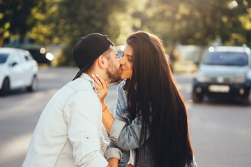 Young, loving parents kiss in the parking near the supermarket.