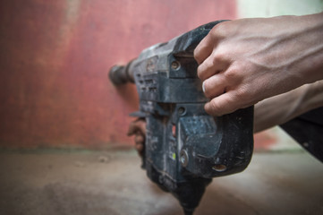The builder works as a puncher, drills a wall.