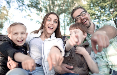 close up.smiling family pointing at you