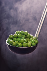 Young green peas with steam on a ladle.Tasty and healthy food.