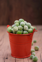 Young green peas in a small bucket on the tableTasty and healthy food.