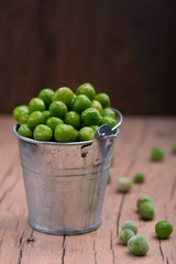 Young green peas in a small bucket on the tableTasty and healthy food.