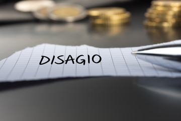 Disagio auf einem Zettel mit Stift vor Geldmünzen