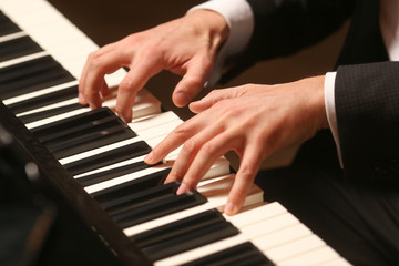 Obraz premium Hands on piano. The pianist plays the piano. Piano keys on black background