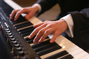 Obraz premium Hands on piano. The pianist plays the piano. Piano keys on black background