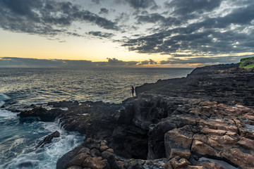 Surf and waves hitting the rock bluff of Makahuena Point, Kauai, Hawaii