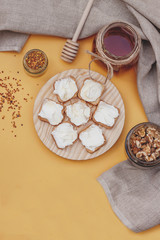 Honey jar between flowers, pollen and honey spoon in yellow background