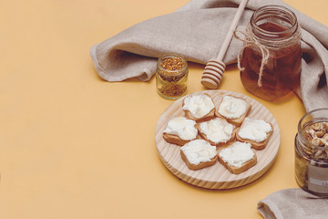 Honey jar between flowers, pollen and honey spoon in yellow background