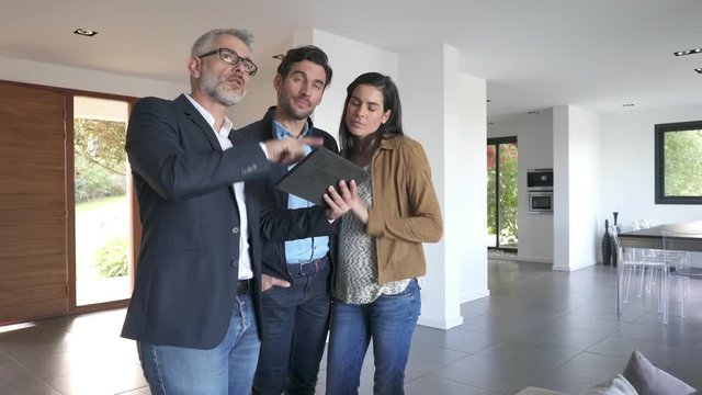 Real estate agent showing modern house to potential buyer couple