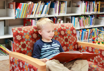 Child reading a library book on a couch
