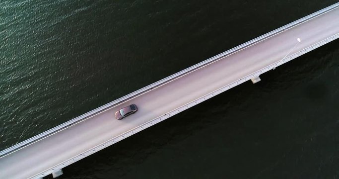 Car on a bridge, C4K aerial, birdseye, drone shot, above a car driving on a asphalt road, in the archipelago, on a cloudy, day, in Varsinais-suomi, Finland