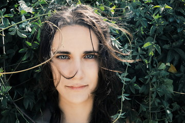 Close-up portrait of a beautiful girl surrounded by plants