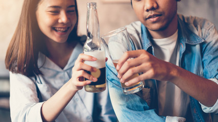 Friends are smiling, happy partying in the bar and talking and clinking bottles with beverages.