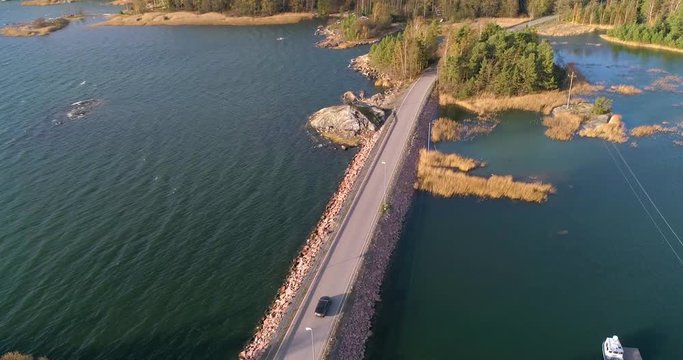 Car on a bridge, C4K aerial, drone shot, following a car driving on a asphalt road, form isoluoto island to sarkisalo, in the archipelago, on a sunny day, in Varsinais-suomi, Finland