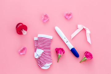 Pregnancy test, socks and hearts pink background top view