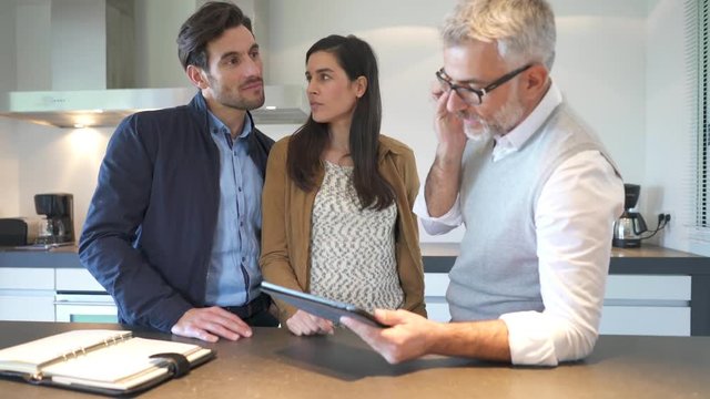 Kitchen rep going through specs on tablet with couple in showroom