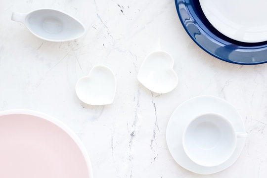 Simple color table setting for celebration with pink and blue plates and heart-shaped saucers on stone table background top view