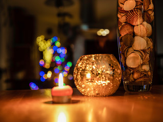 The vase with sea shells near candle and nice blur Christmas lighting