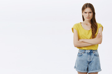 Angry insulted pressured attractive girl in yellow t-shirt and shorts holding hands crossed on...