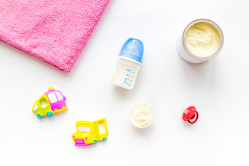 Baby care with craft toys for newborn. Rattle and powdered milk. White background top view