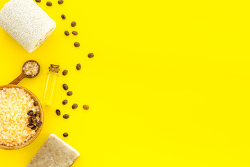 Aromatherapy and spa concept. Spa salt with coffee scent near soap and loofah on yellow background...