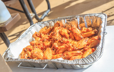 Fried Naked Chicken Wings: Fried naked chicken wings in a foil tray just after being cooked.