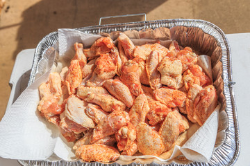 Raw Seasoned Chicken Drummettes and Flats:  Raw seasoned chicken drummettes and flats in a foil tray prepared for cooking.