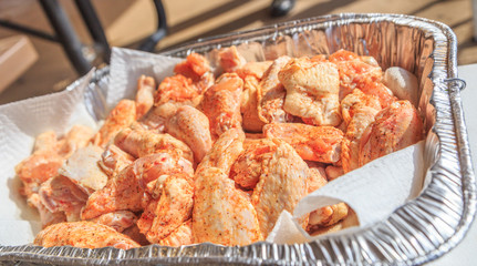 Raw Seasoned Chicken Drummettes and Flats:  Raw seasoned chicken drummettes and flats in a foil tray prepared for cooking.