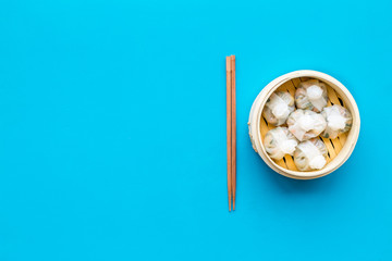 Dinner in Chinese restaurant with dim sum, sticks on blue background top view space for text