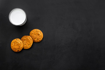 Children tradition evening dessert. Milk and homemade cookies on black background top view space for text