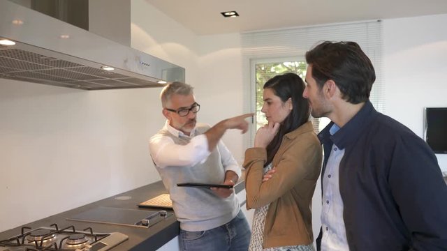 Kitchen salesman pitching to potential buyer couple in showroom