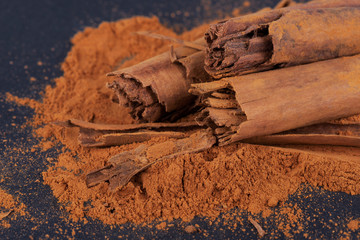Sticks and ground ceylon cinnamon on dark background.