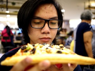 Asian teen eating a big pizza