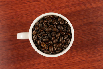 Coffee beans in white cup with wooden background