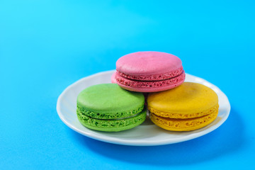 White Cup cakes with colorful macaroons on blue fanene.