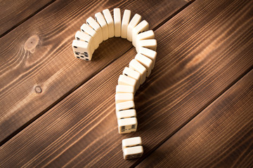 Domino question mark on wooden table. Domino principle