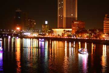 Cairo by night at the nile river with boats at the river and beautiful lights with color reflection