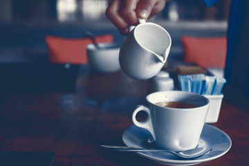 pouring milk to the cup of coffee