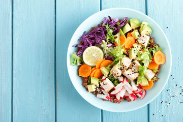 Bowl with grilled chicken meat, brown rice and fresh vegetable salad of avocado, radish, cabbage...