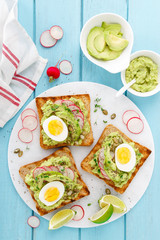 Toasts with avocado guacamole, fresh radish, boiled egg, chia and pumpkin seeds. Diet breakfast. Delicious and healthy plant-based food. Flat lay. Top view