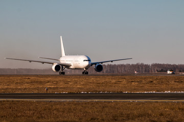 White wide body passenger airplane moves behind the Follow-me-Car on the main taxiway