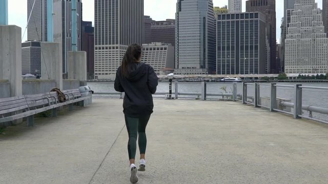 Attractive young fit woman jogging running exercise on the pier in New York. Slow Motion.