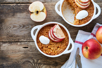 Rice casserole with apples and carrots on a wooden background
